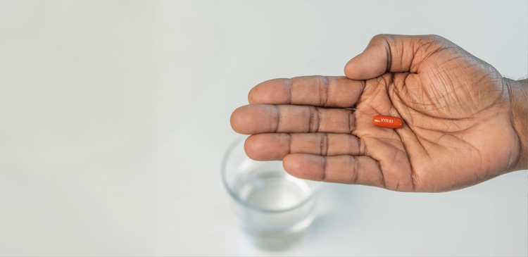 A hand with palm facing up holding a VYNDAMAX (tafamidis) pill
