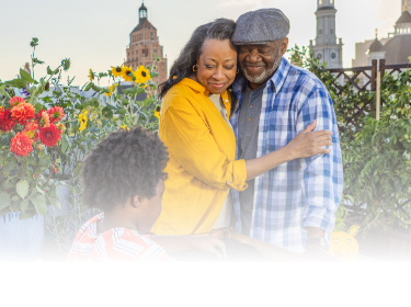 Actor portrayal of an older adult couple hugging watching their grandchild