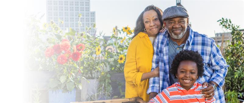 Actor portrayal of an older adult couple with their grandchild smiling at the camera