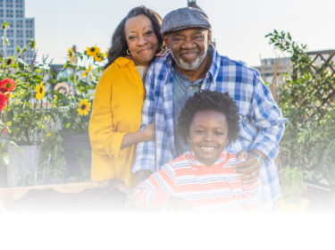 Actor portrayal of an older adult couple with their grandchild smiling at the camera