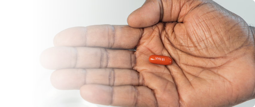 A hand with palm facing up holding a VYNDAMAX (tafamidis) pill